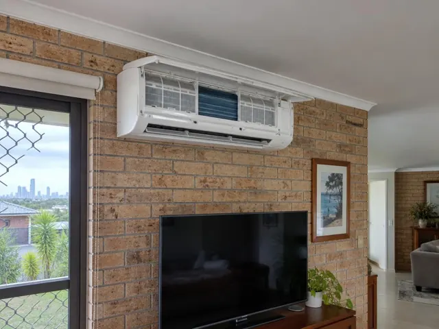 Open split system air conditioner with visible filters on a brick wall in a living room in Coolangatta